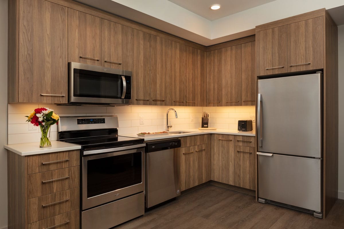 The Shore Kelowna 2 bedroom den suite kitchen, including wooden cabinets and stainless steel appliances