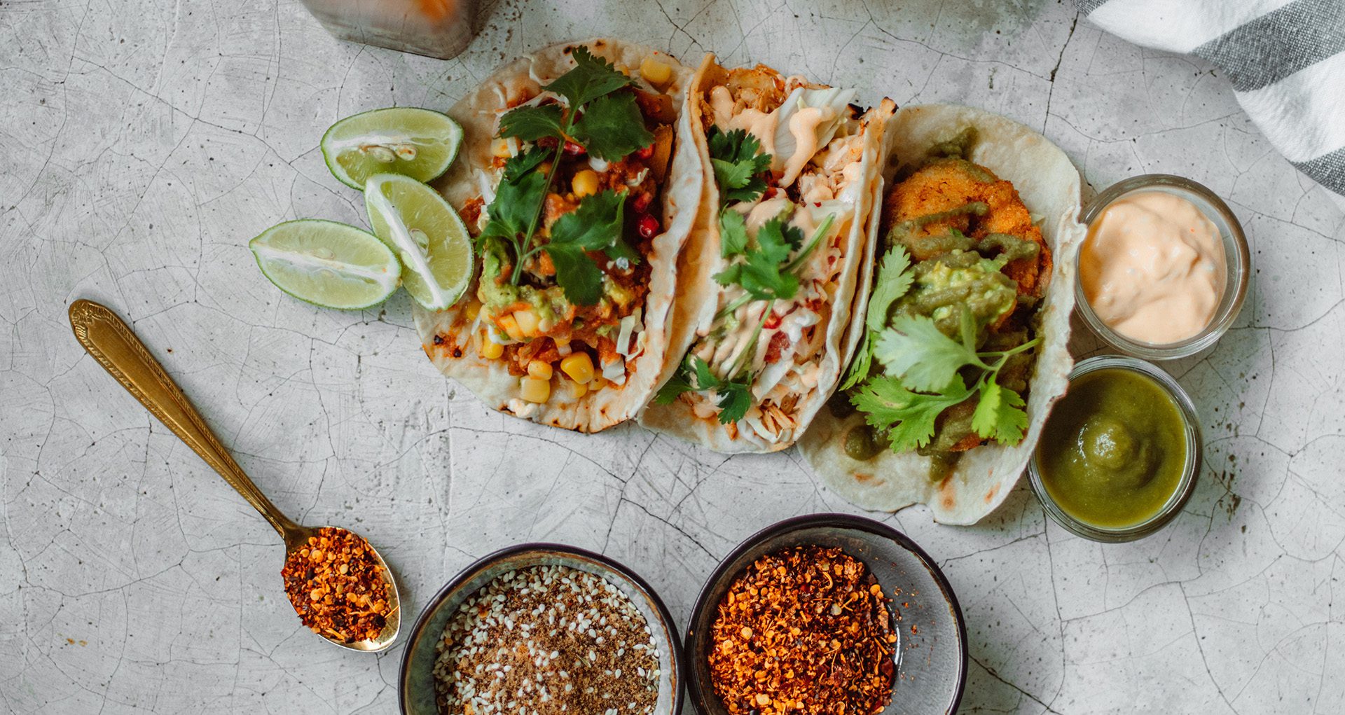 mexican food in kelowna spread out on a quartz counter, including 3 tacos, sauces and spices