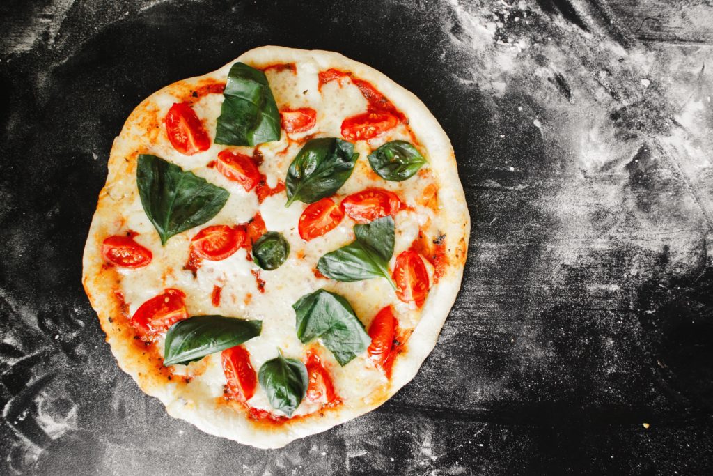 an authentic margarita pizza on a floured granite countertop