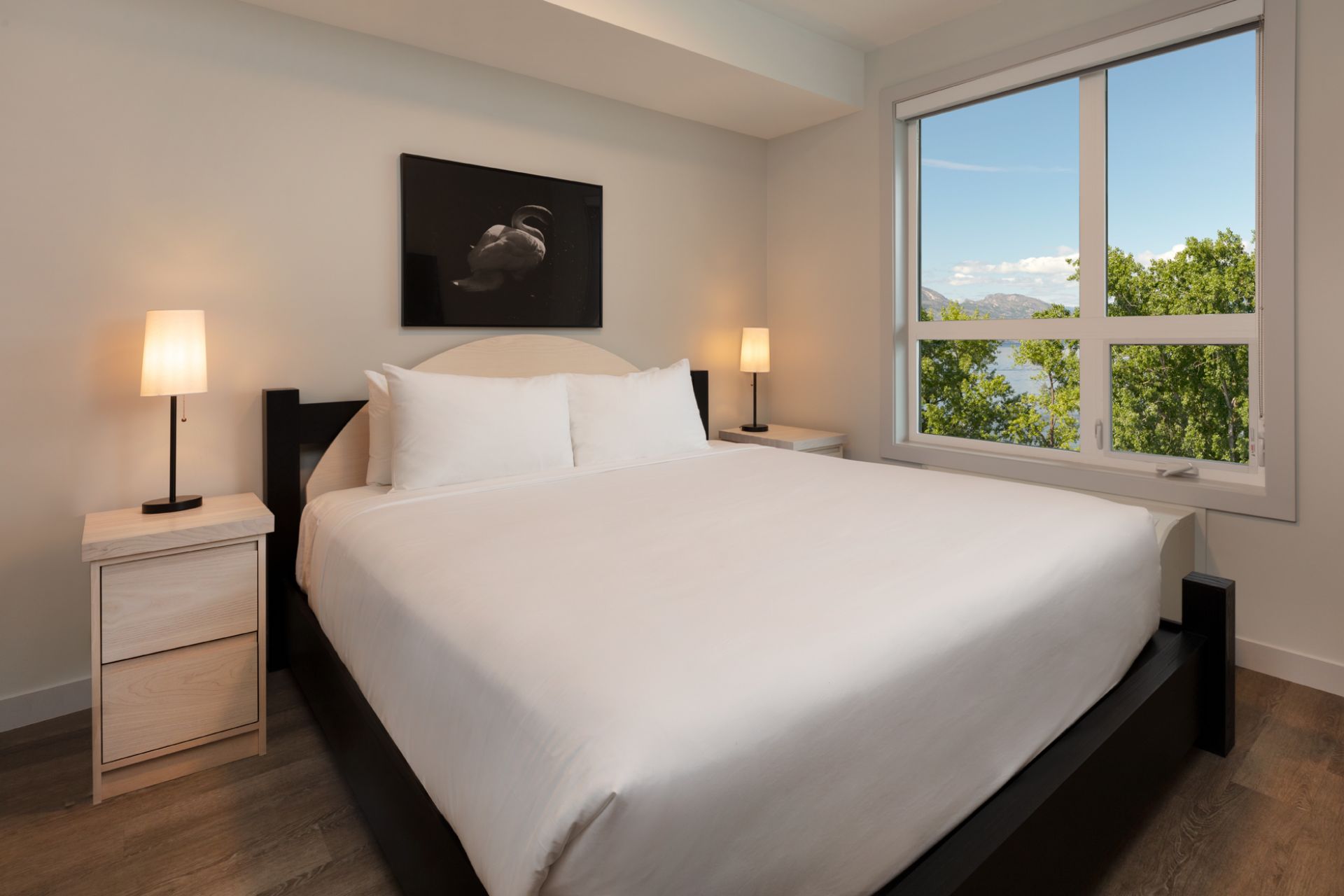 the king bed in the 1 bedroom suite at The Shore Kelowna, with two side tables and lamps