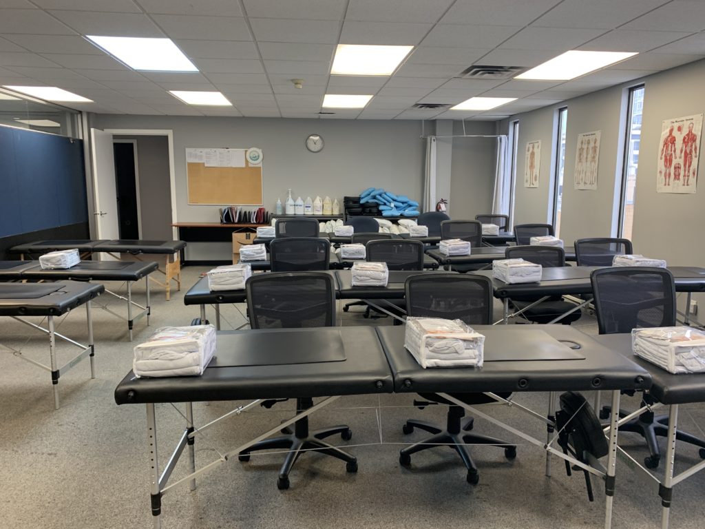massage table desks at first college massage therapy, with a classroom prepped for class with sheet sets at each station
