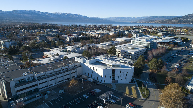 an exterior view of okanagan college from above, showing the lake and valley views in the background