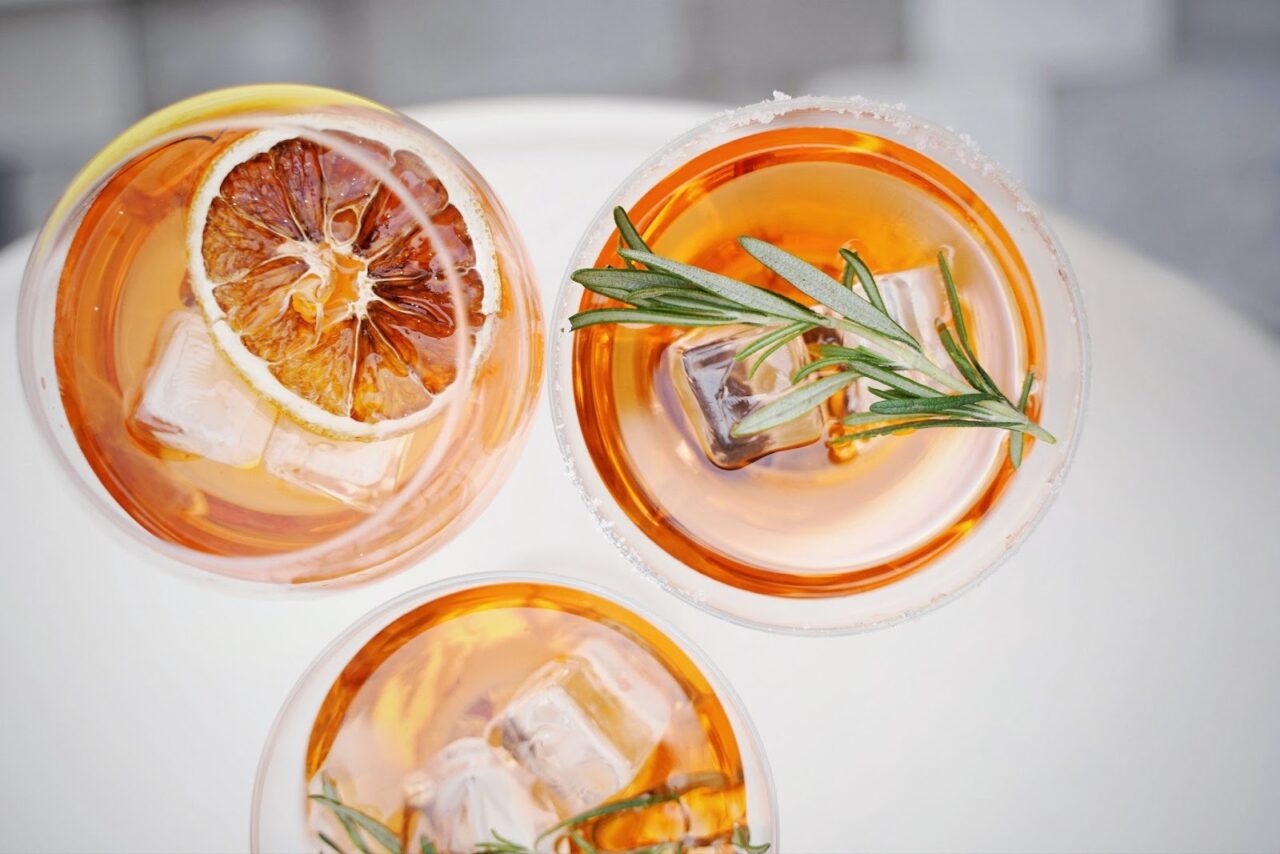 orange hued cocktails with dried orange and rosemary garnishes at a happy hour in kelowna