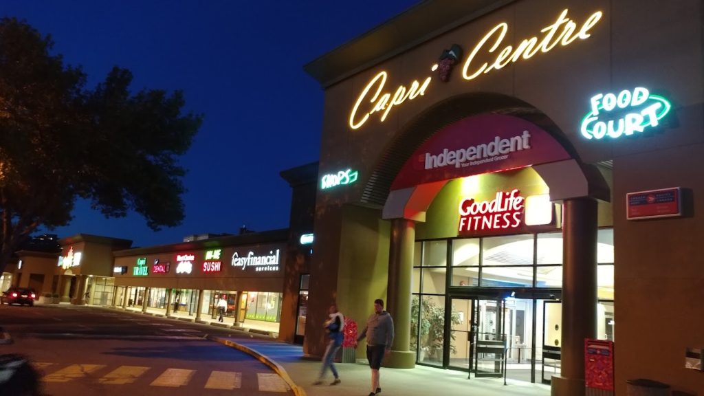 a night time view of capri centre mall with neon lights highlighting the different stores
