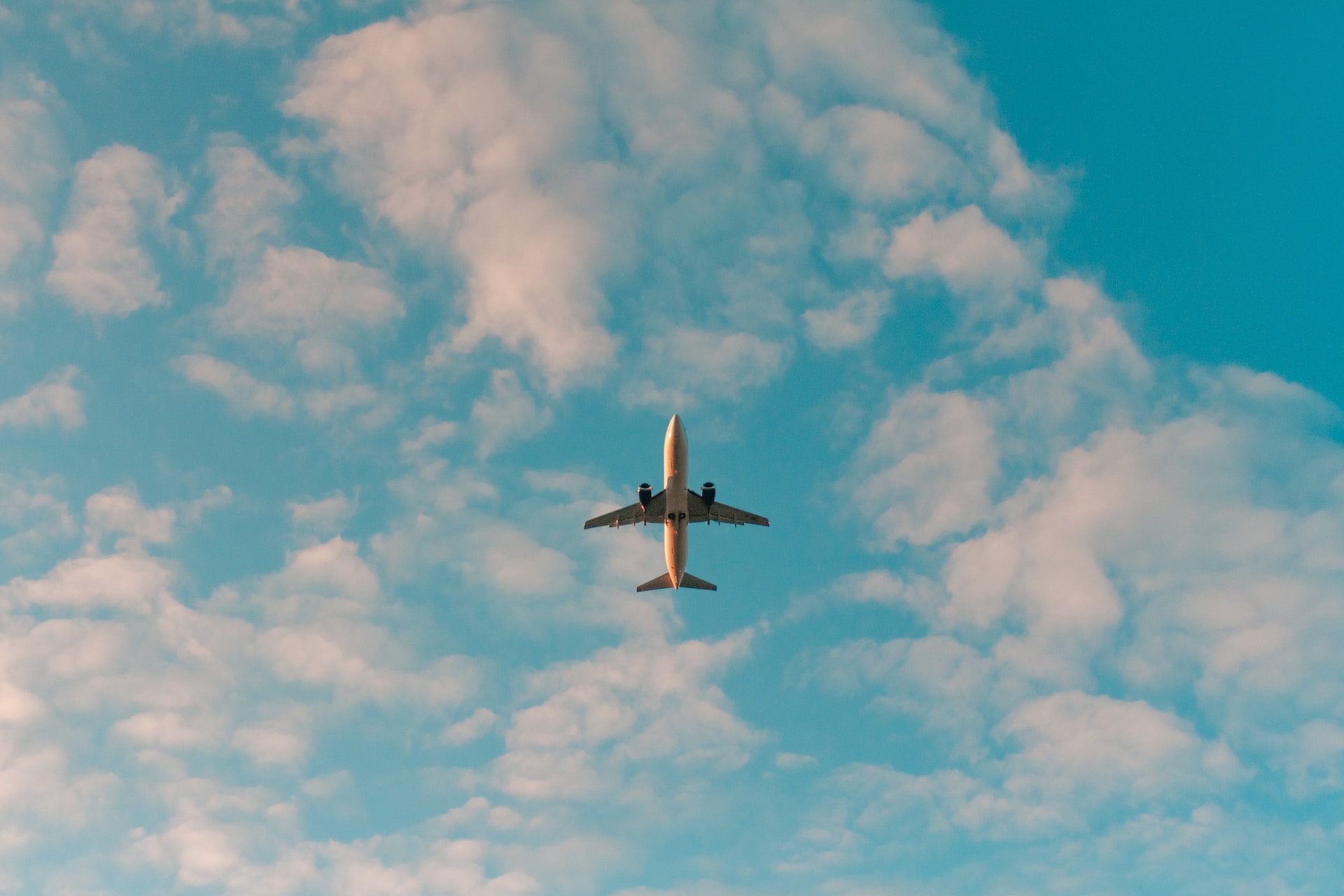 a bottom-up view of an airplane at the kelowna airport YLW flying on a sunny day with fluffy white clouds surrounding