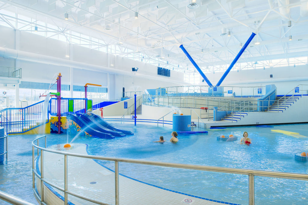 an interior view of the pools at the Kelowna H2O aquatic centre with moms and kids playing in the water