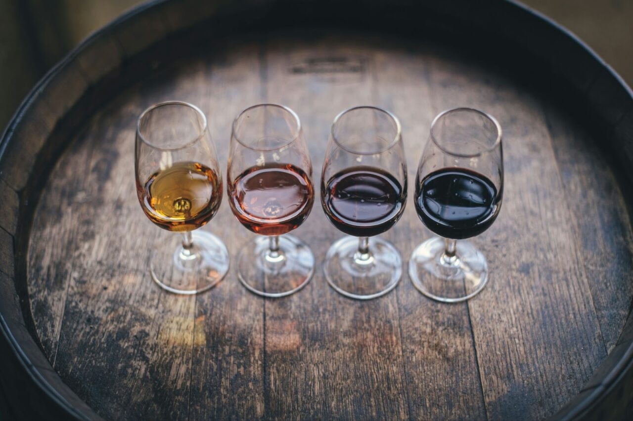 Four glasses of wine on top of a wooden barrel at a wine tasting that is just one of the events Kelowna has to offer.