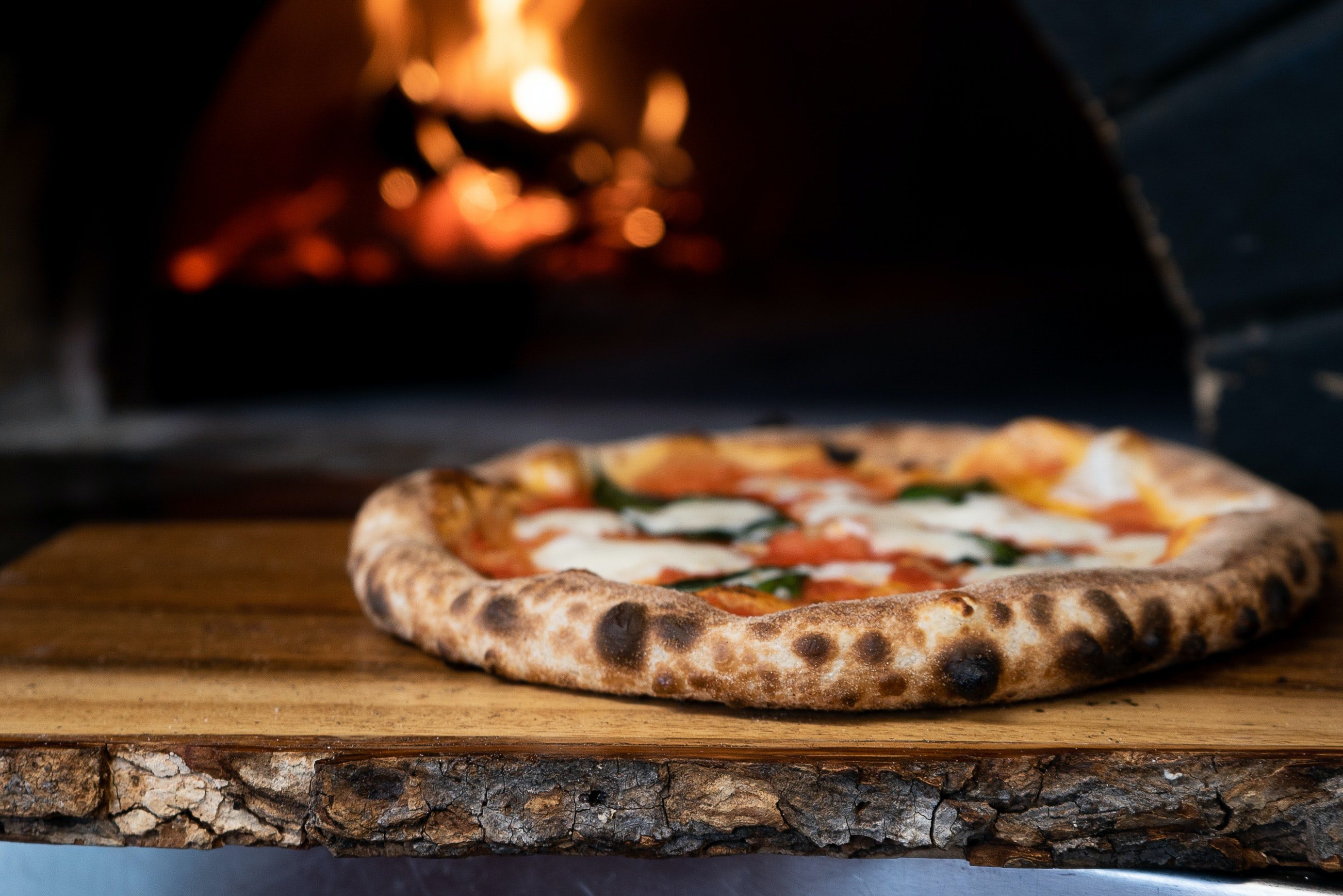 a pizza coming out of a woodfire oven, highlighting the best pizza in kelowna
