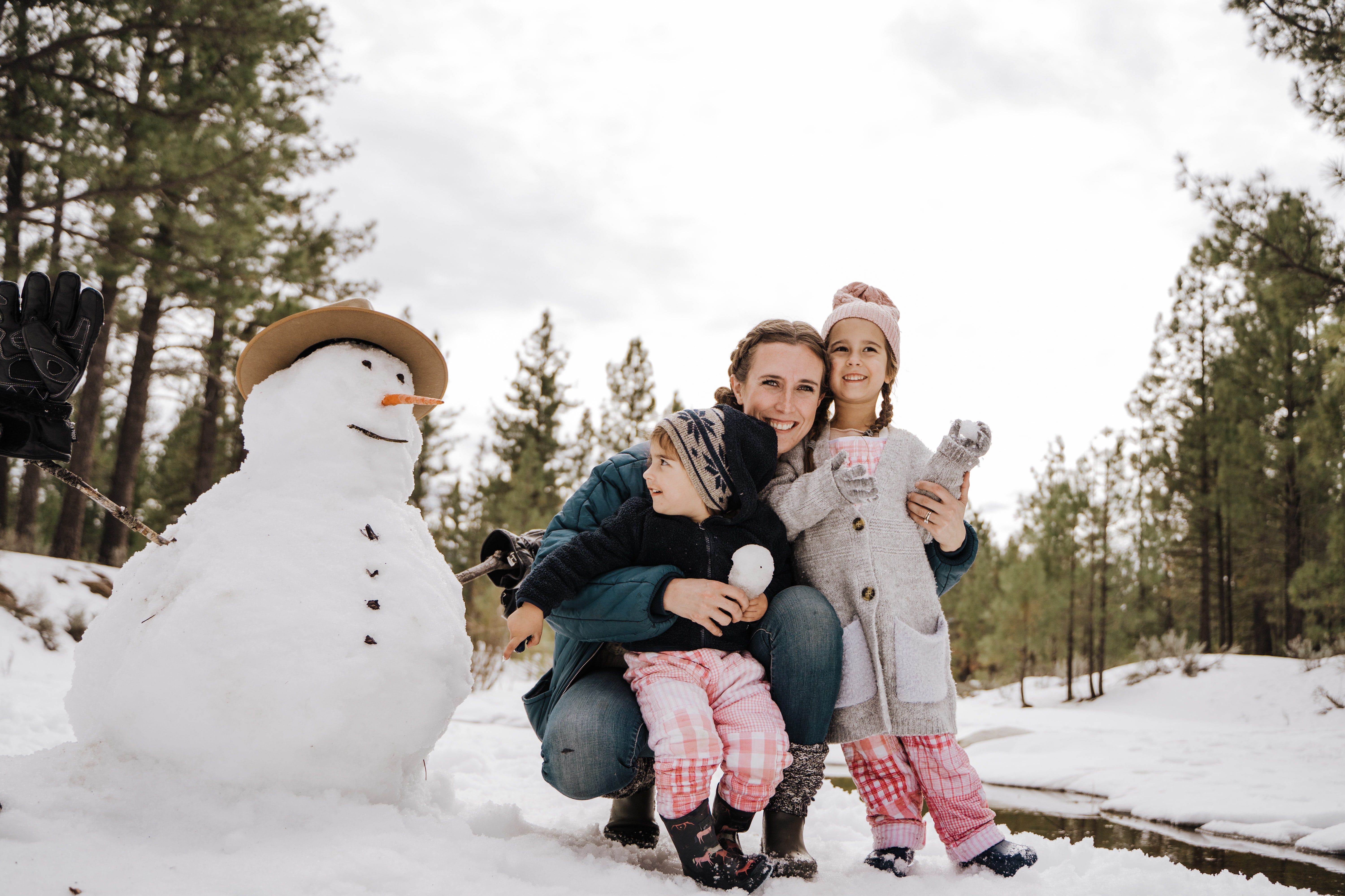 a mother and two children posing for a photo next to a snowman in kelowna over christmas holidays