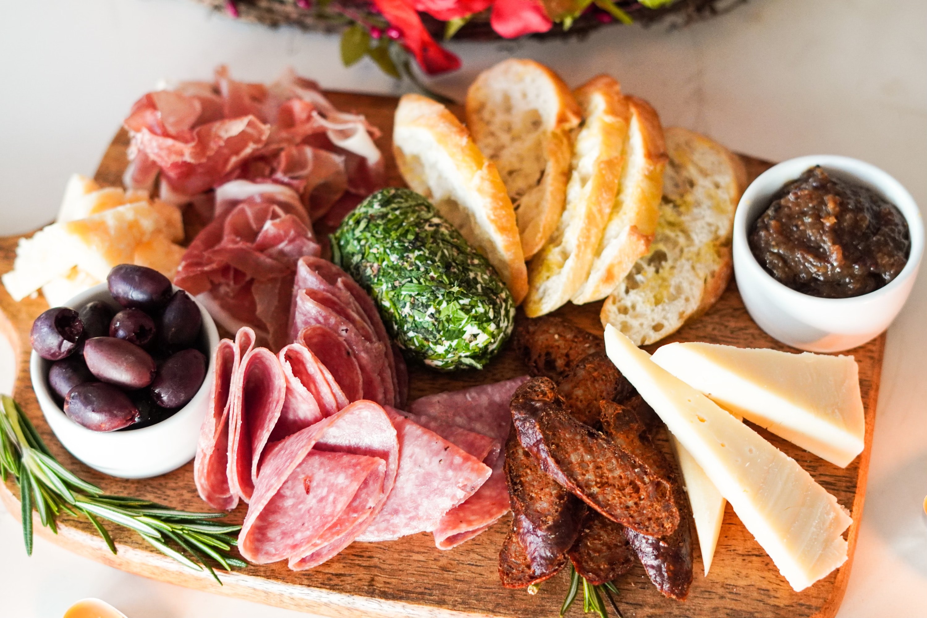 a charcuterie board with baguette slices, meats, cheeses and spreads