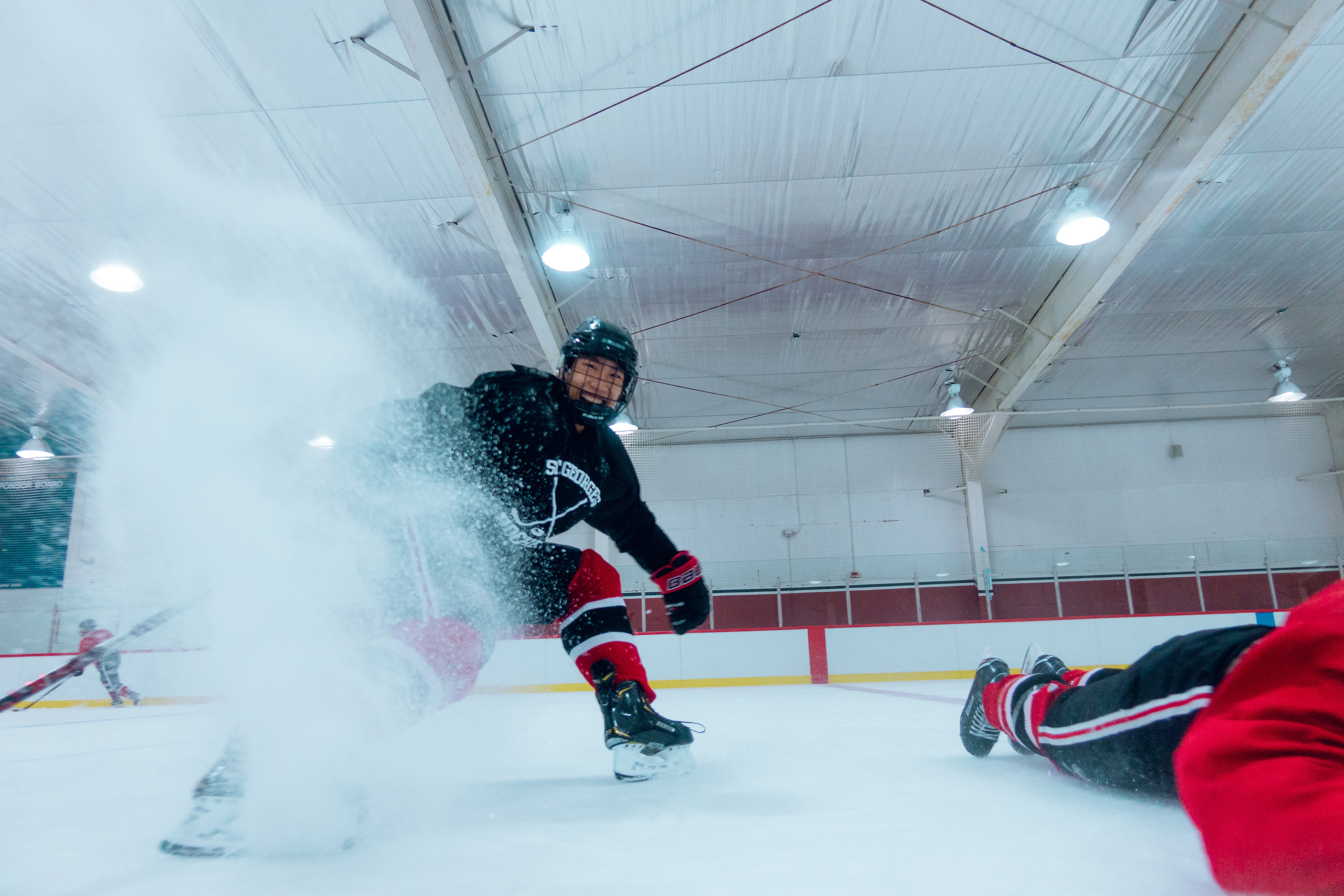 a young hockey player in a Kelowna ice rink, kicking up ice with his skate towards the camera