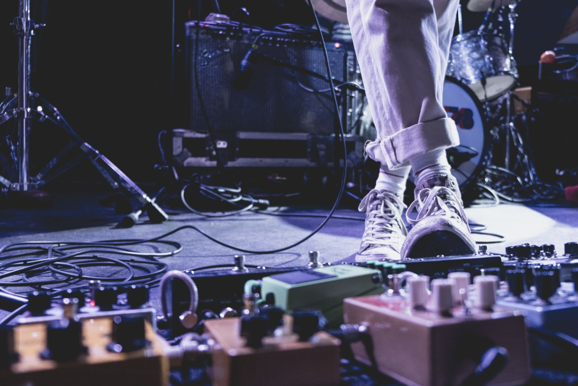 closeup of a musician's feet pushing pedals on a stage with amps in the background, highlighting the live music scene in Kelowna