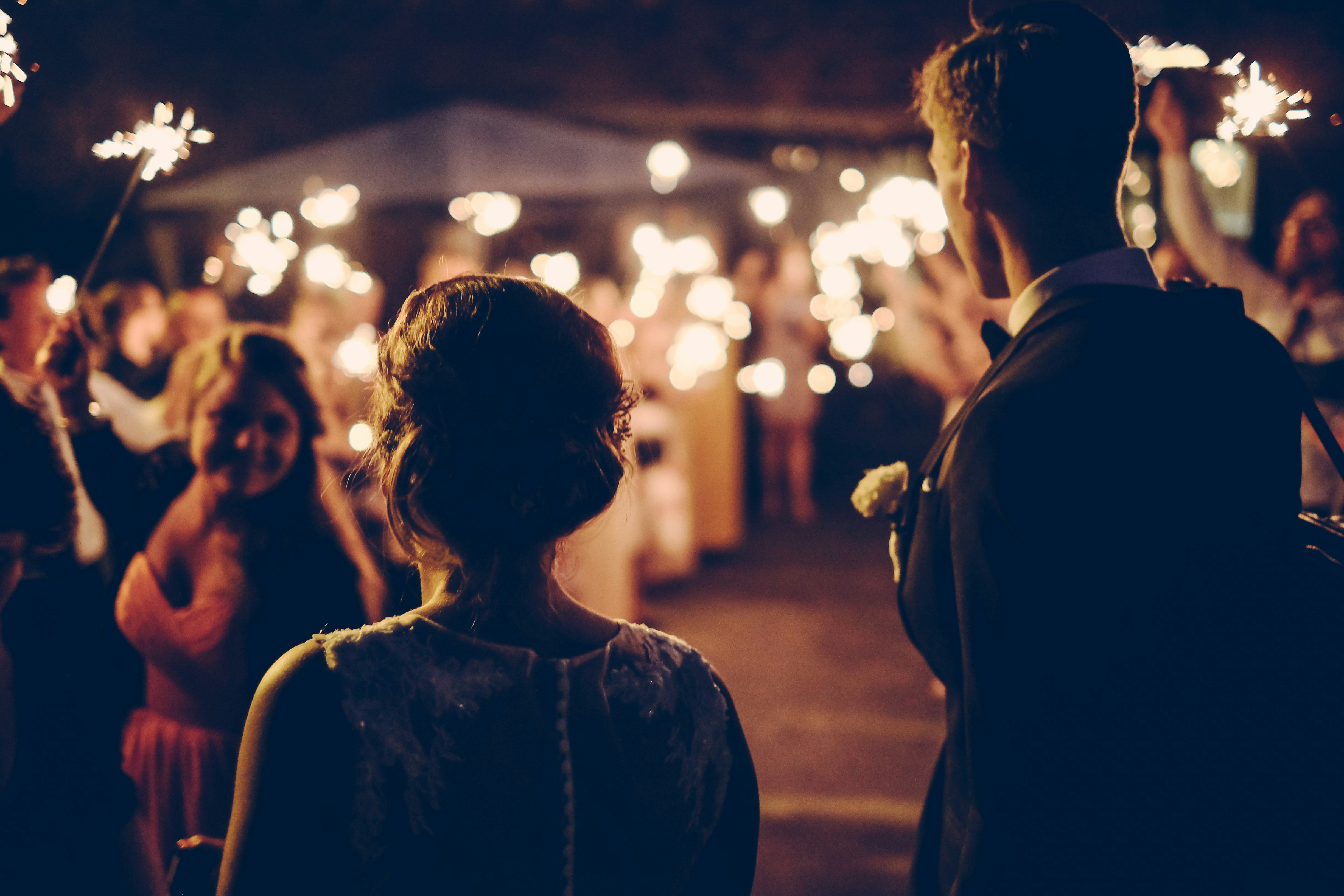 Two people standing in front of soft focus twinkle lights on their wedding day